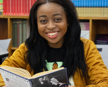 Nicole Satchell smiles while reading a book.