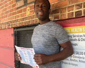 Gavin holds up a schedule for the CONNECT program outside a building entrance.