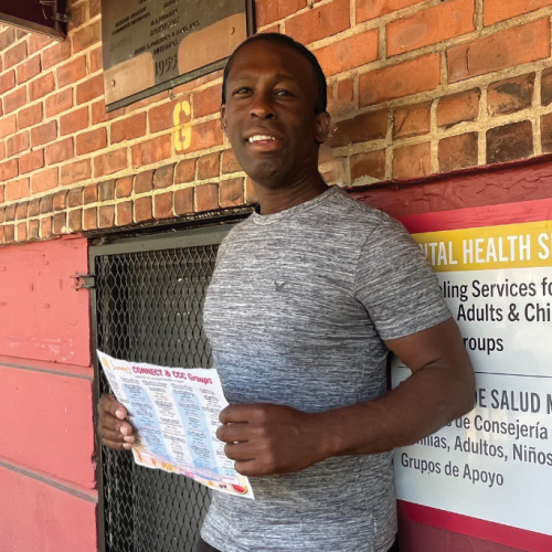 Gavin holds up a schedule for the CONNECT program outside a building entrance.