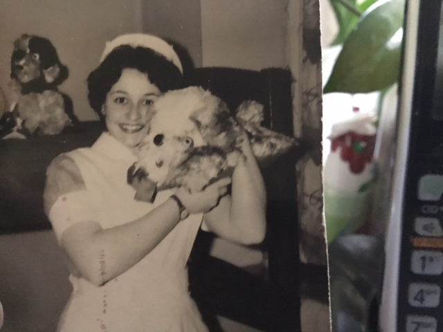 Black and white image of Enid Zwirn in nurse uniform holding up a dog on the right shoulder